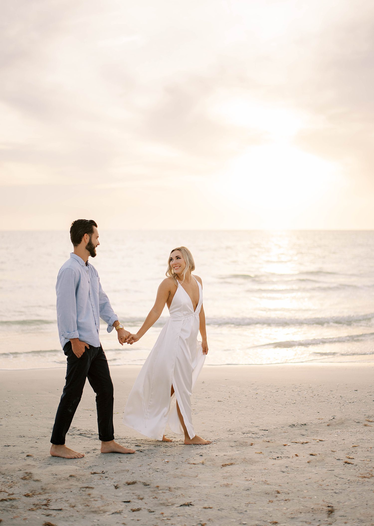 woman leads fiancee across beach during St. Pete engagement session