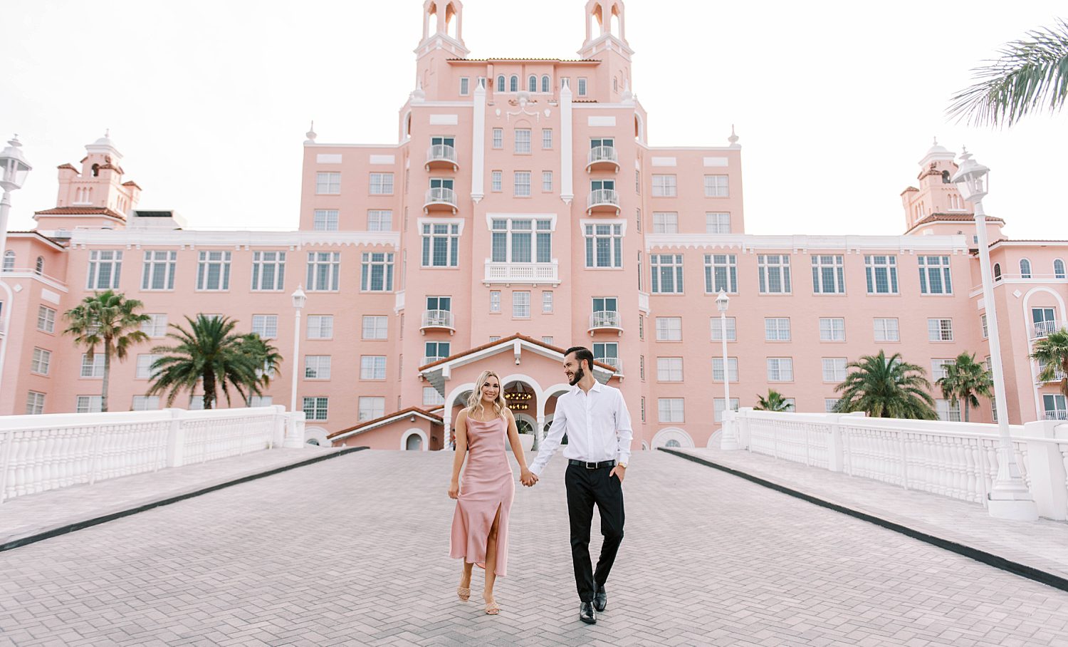 engaged couple holds hands walking outside the Don Cesar Hotel in St. Pete beach 