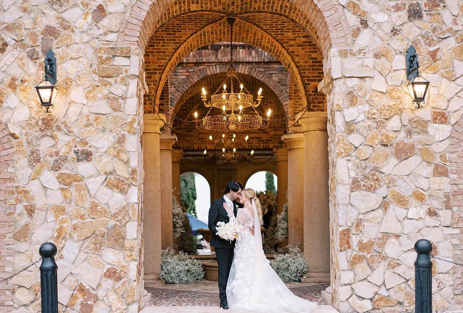 bride and groom kiss in stone archway at Bella Collina