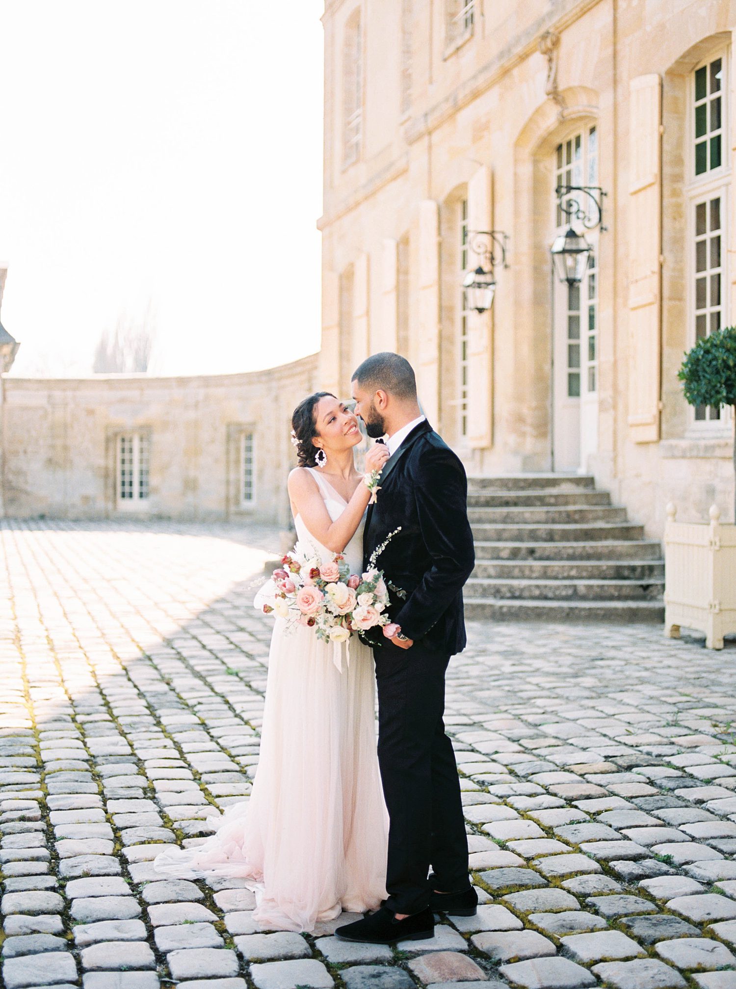 bride and groom hug in courtyard of Chateau de Villette