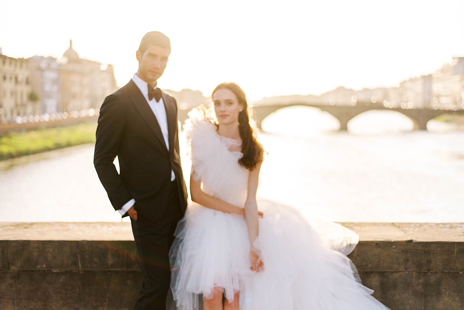 bride and groom pose along historic bridge in Florence at sunset
