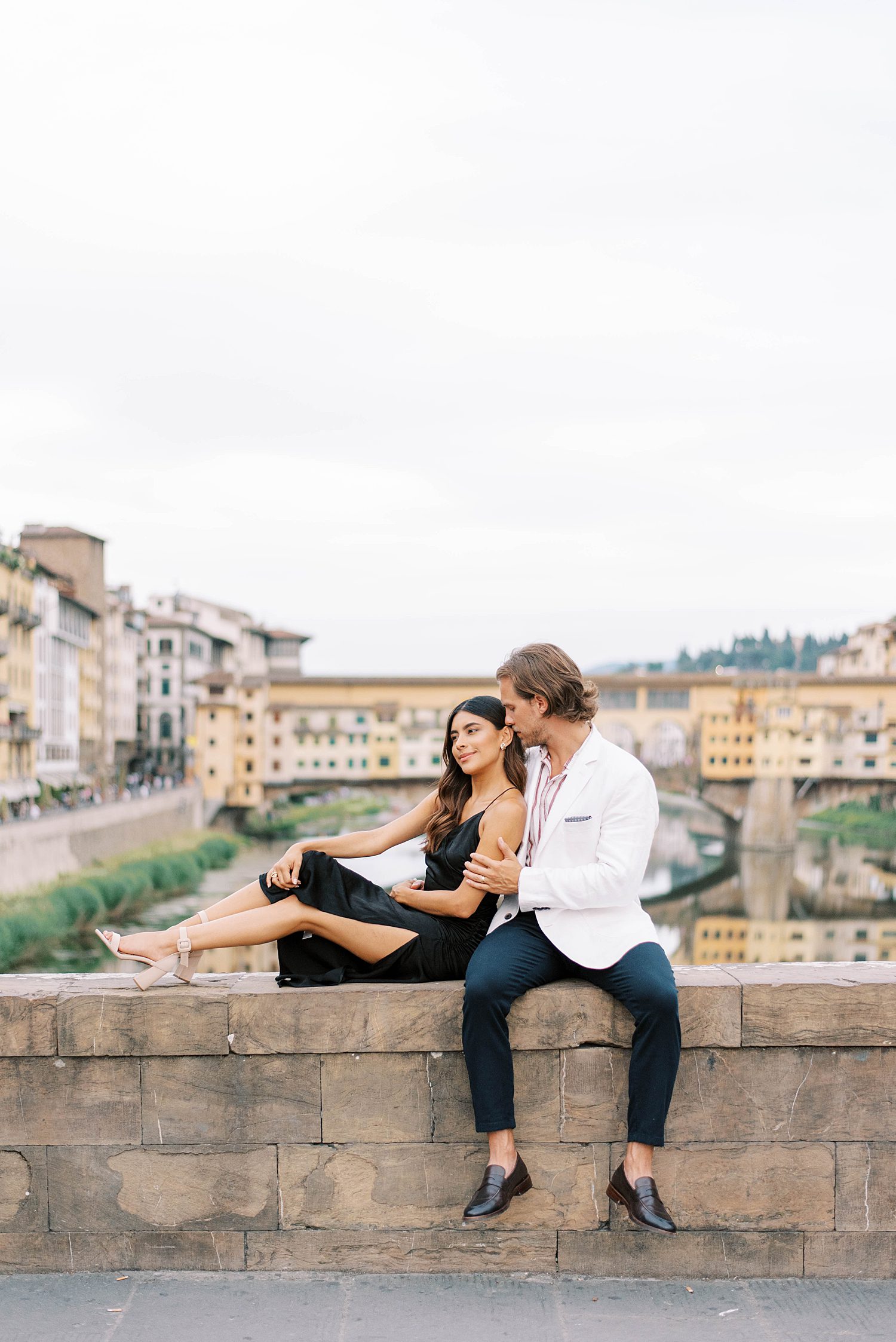 newlyweds sit on bridge at Ponte Vecchio