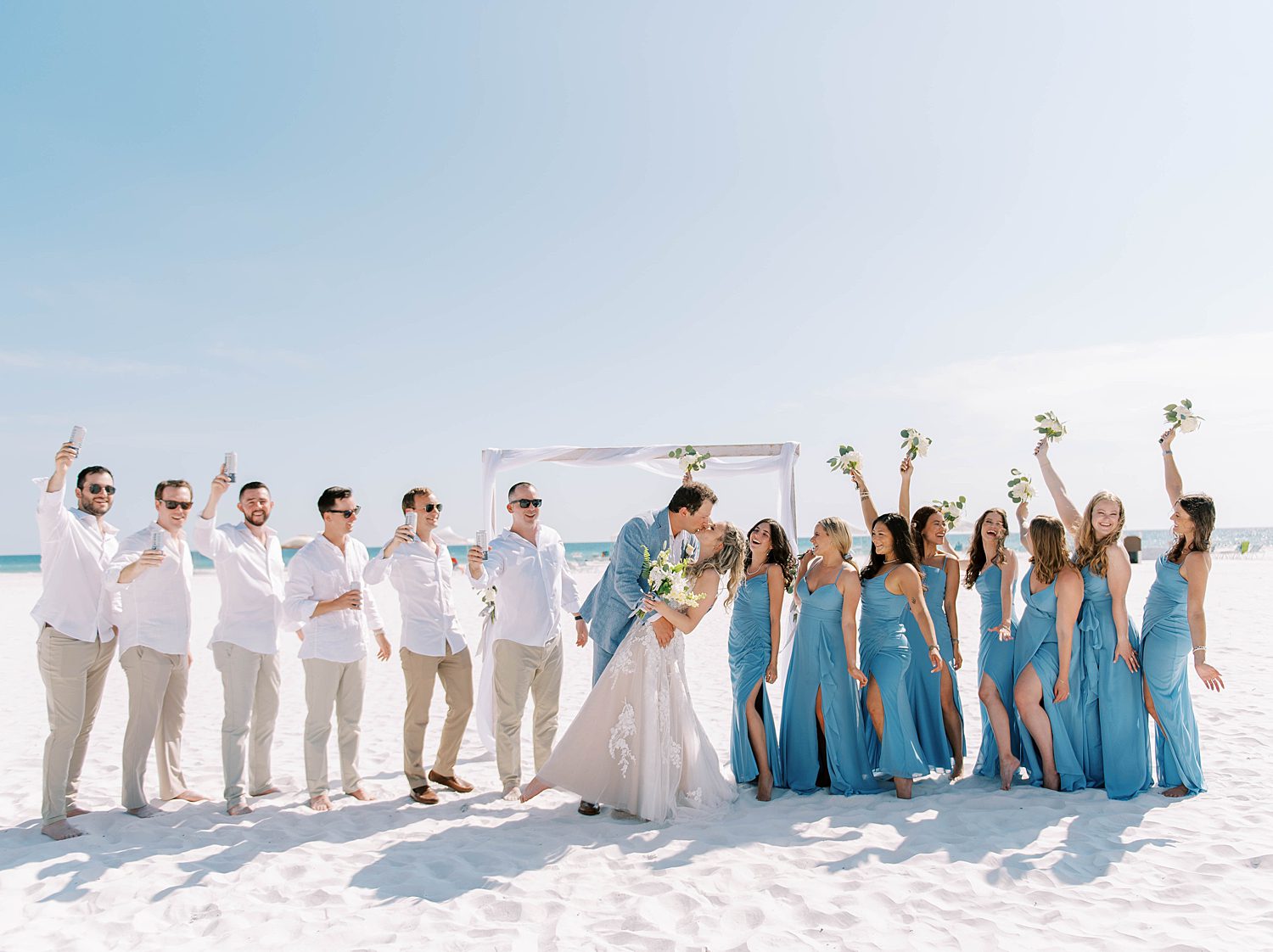 newlyweds kiss on Siesta Key Beach while bridal party cheers