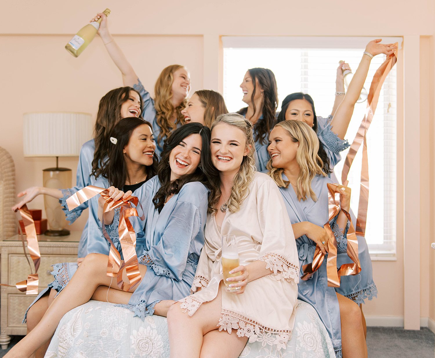 bride and bridesmaids cheer with champagne during prep on wedding day