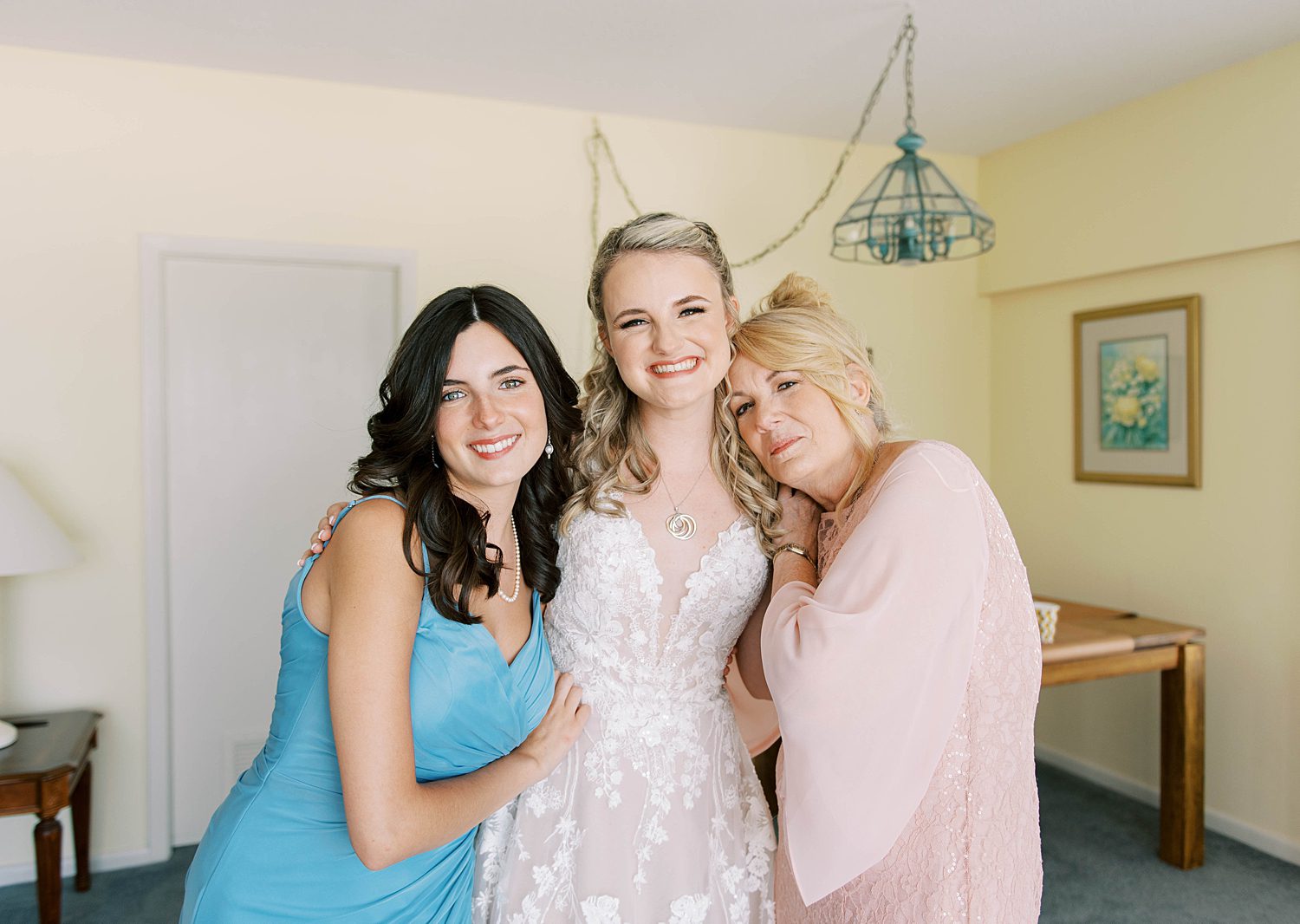 mother and sister help bride into wedding gown