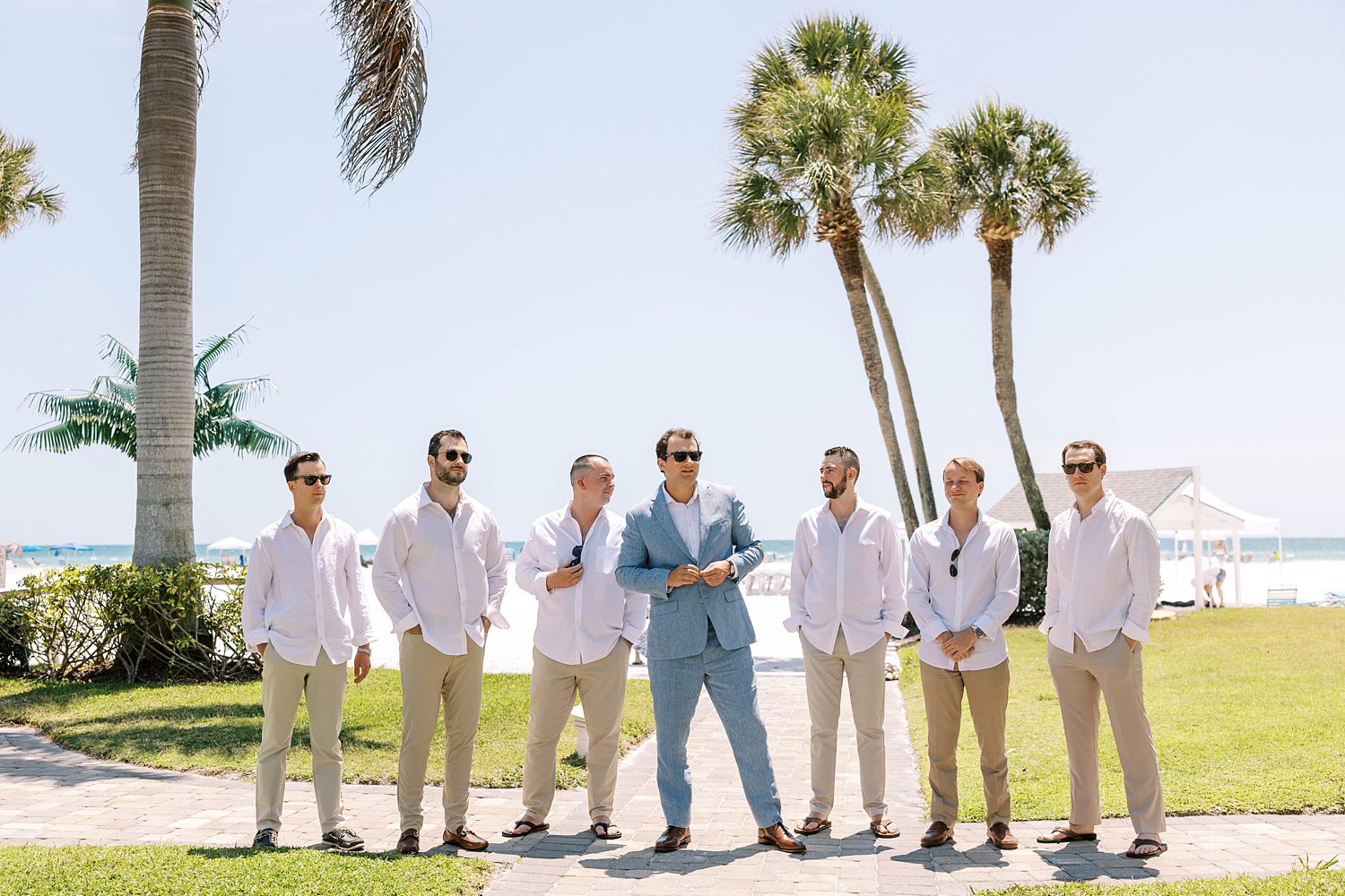 groom stands with groomsmen in white linen shirts and khakis 