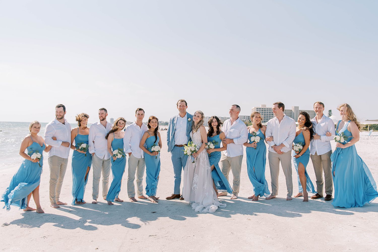 newlyweds stand with wedding party on beach in Florida