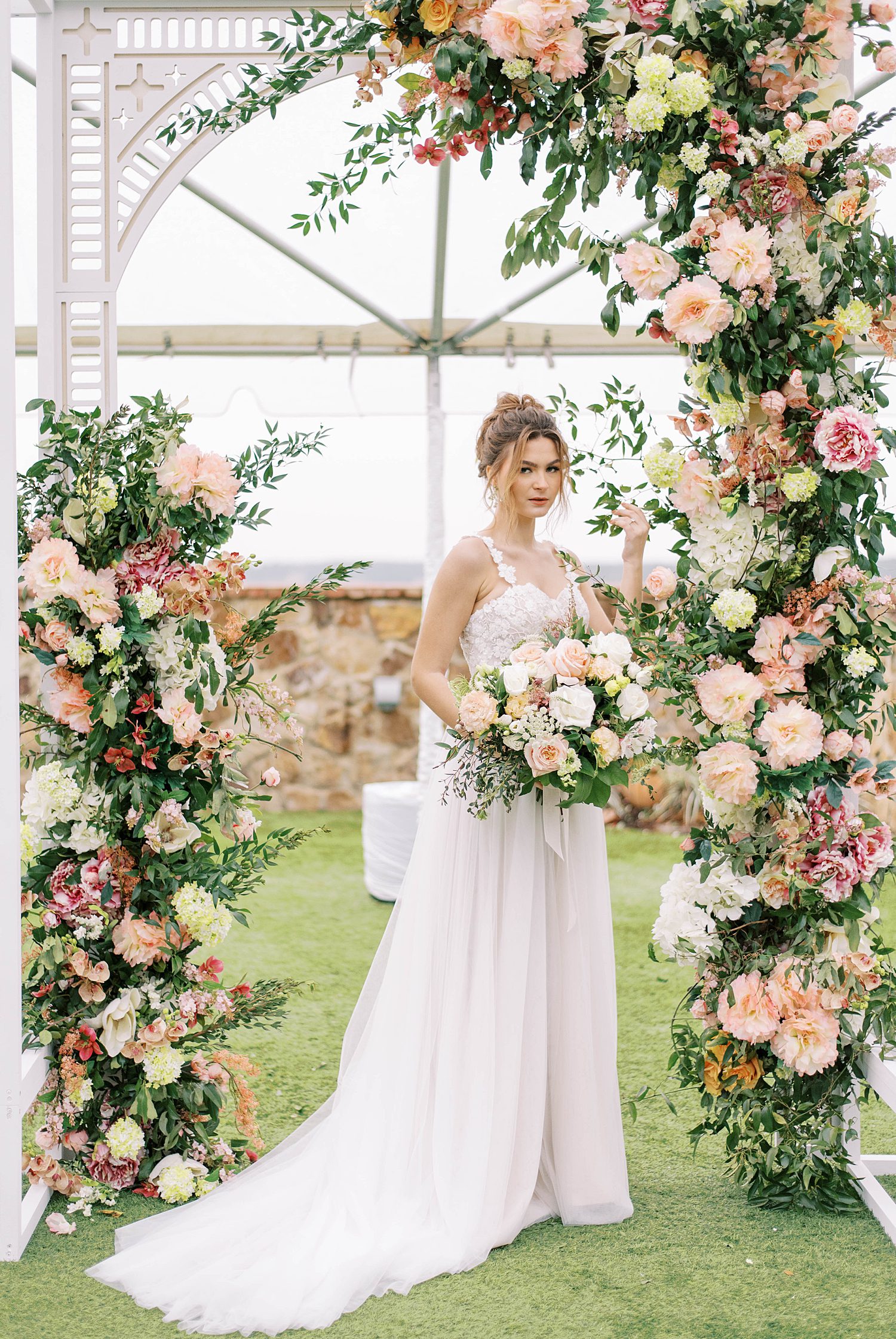 bride stands under arbor during garden wedding at Bella Collina