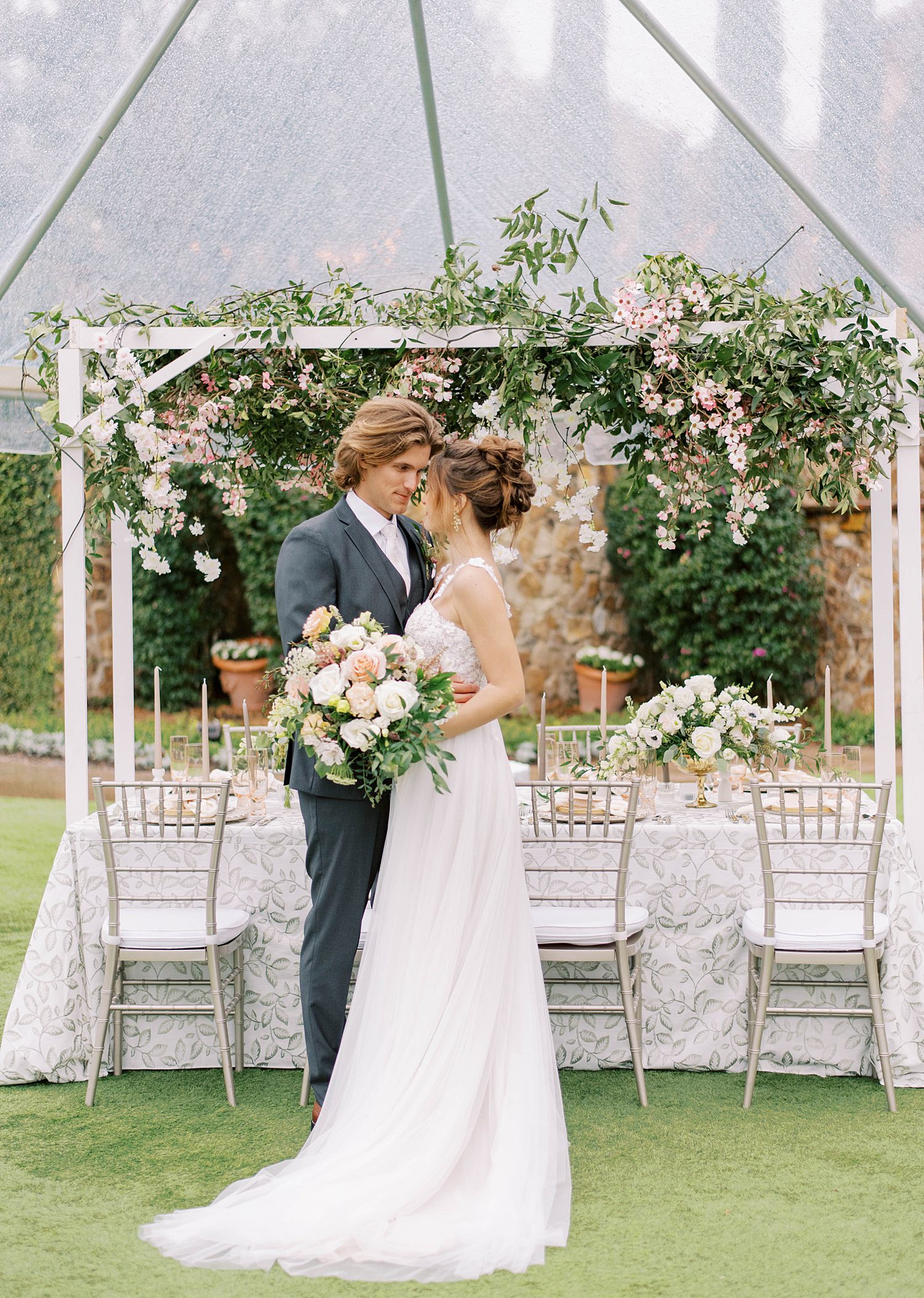 newlyweds pose by table during garden wedding at Bella Collina