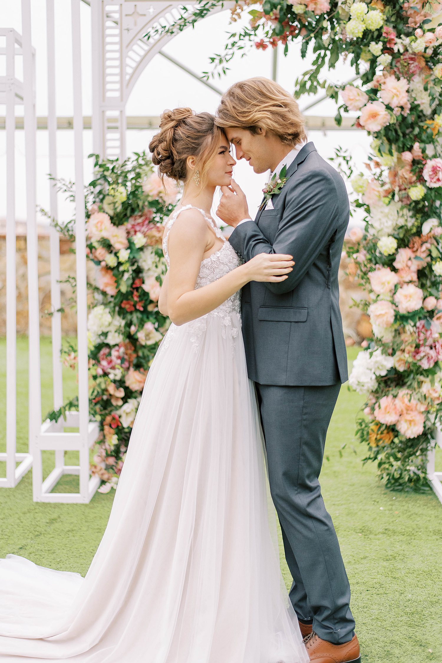 bride and groom stand together by white arbor during garden wedding at Bella Collina