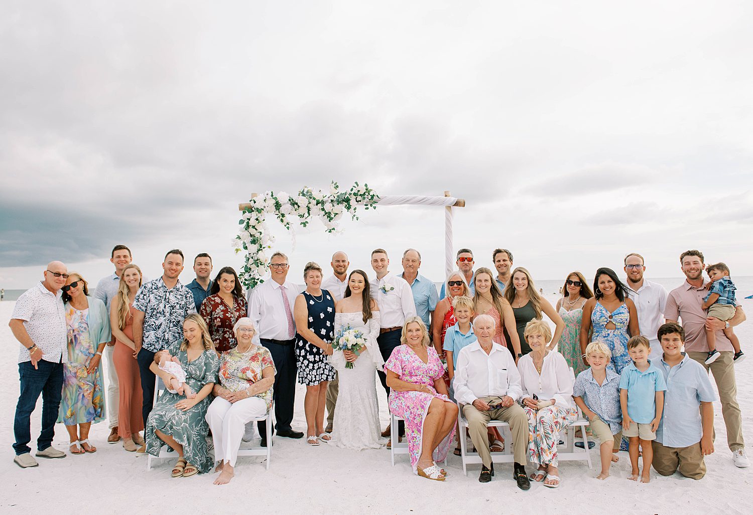 bride and groom pose with guests from beach wedding