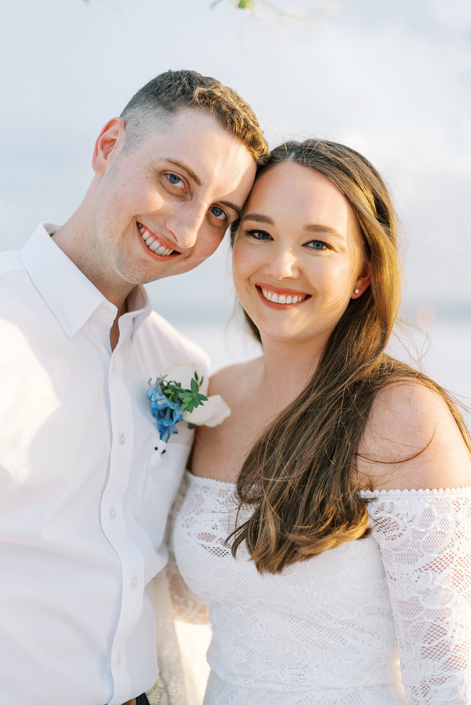 newlyweds lean heads together standing on beach at Lido Key Beach