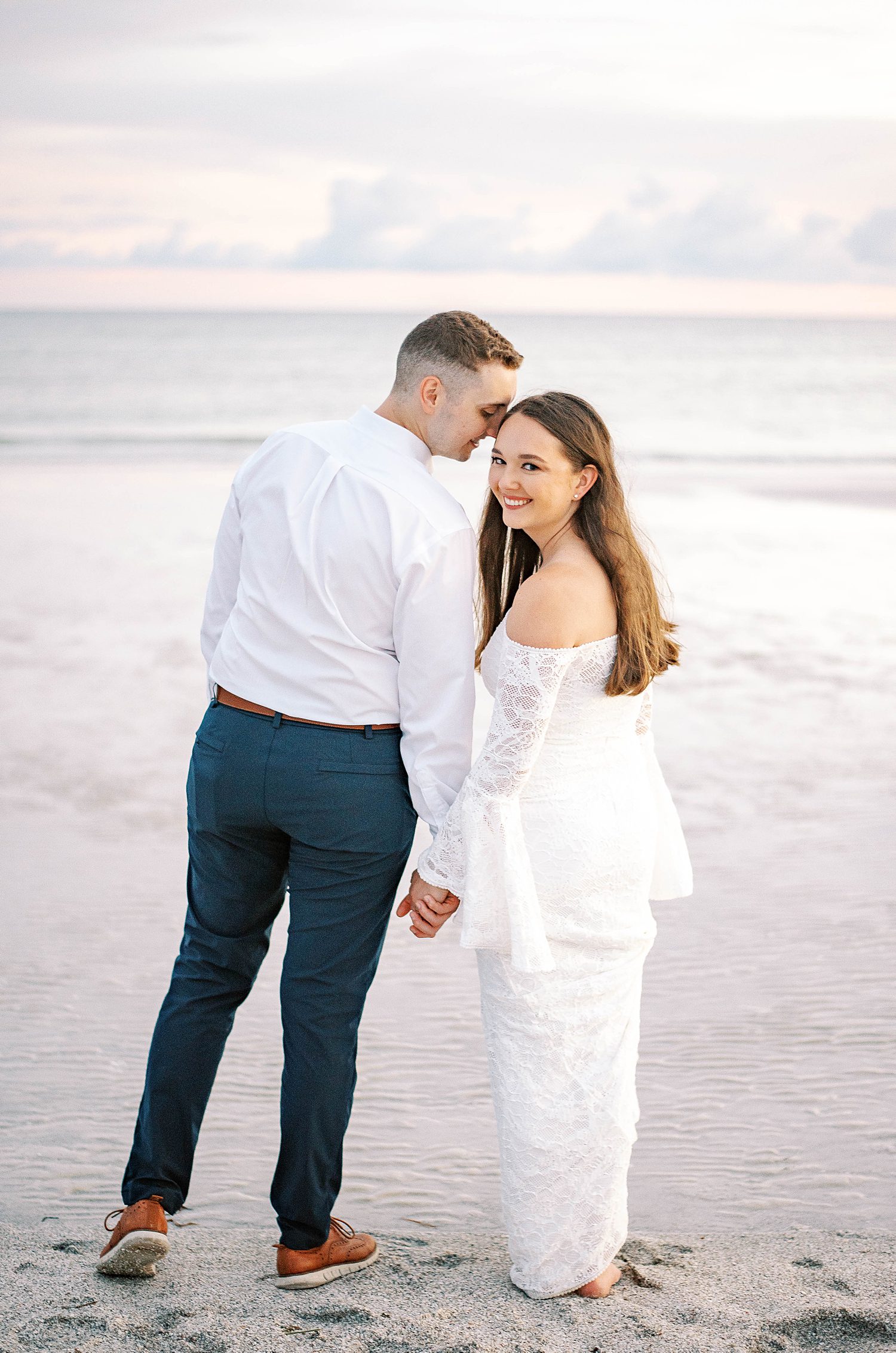 groom leans to nuzzle bride's forehead on Lido Key Beach