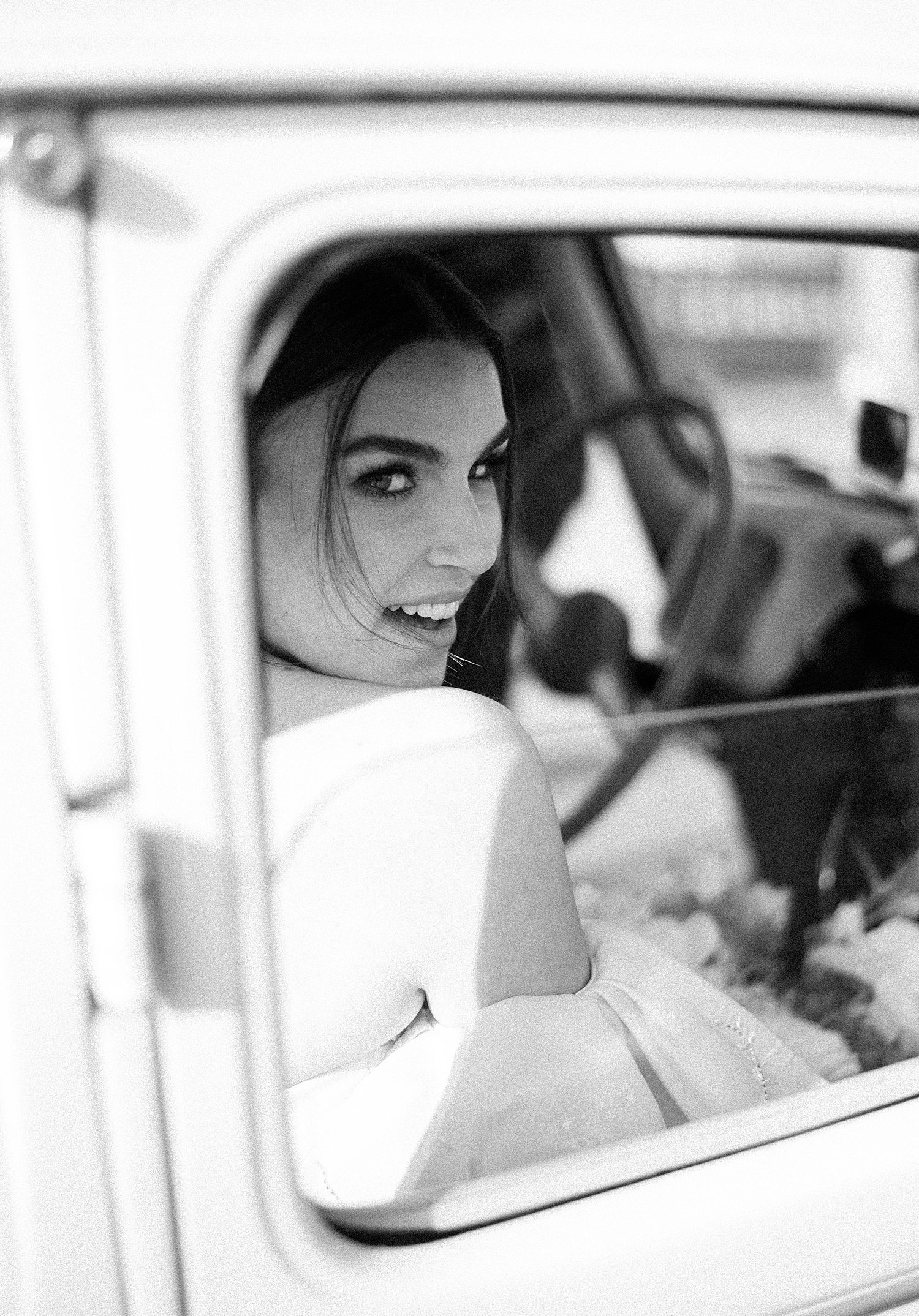 black and white portrait of bride looking over shoulder out car window