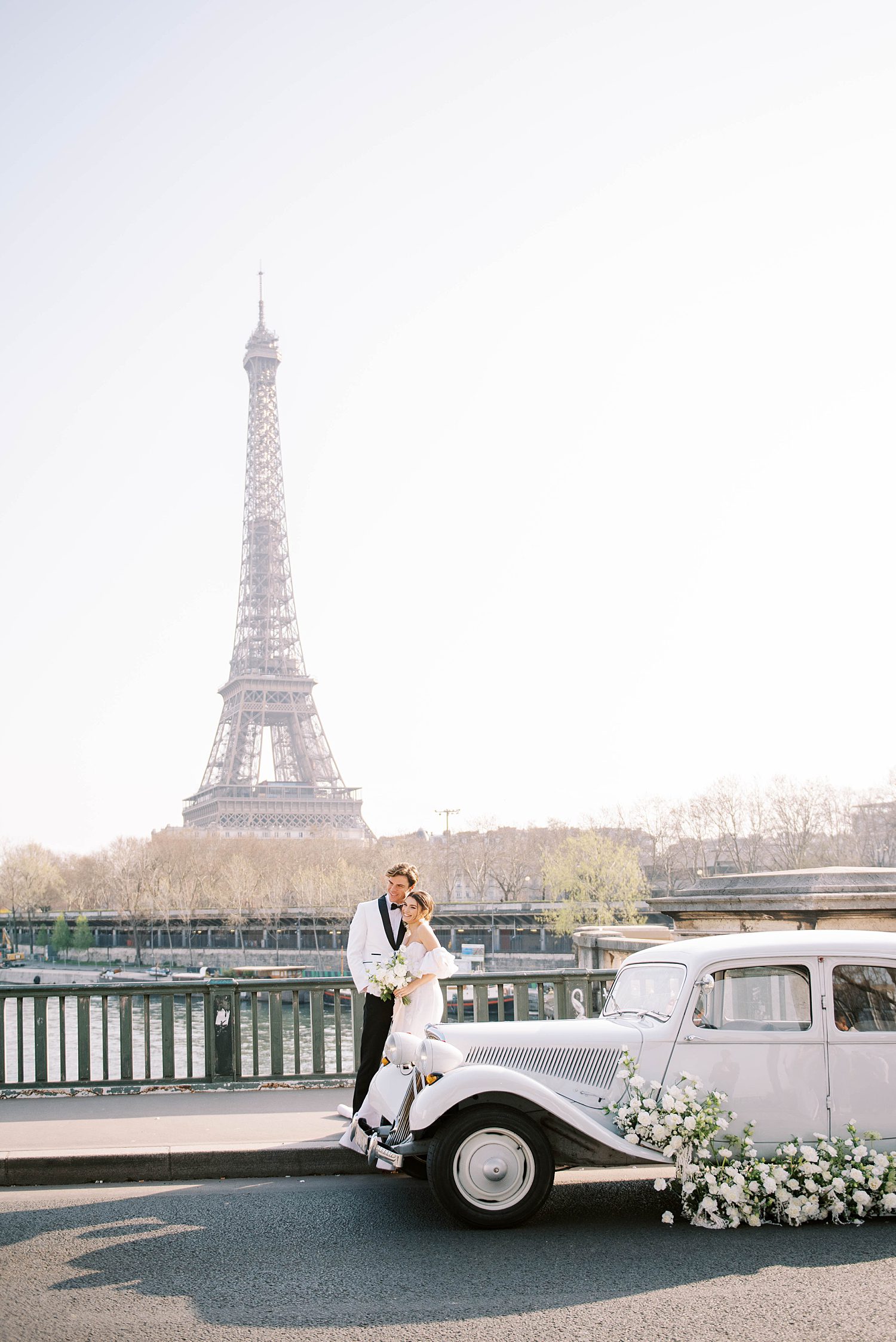 romantic Paris elopement by Eiffel Tower with classic white car next to bride and groom