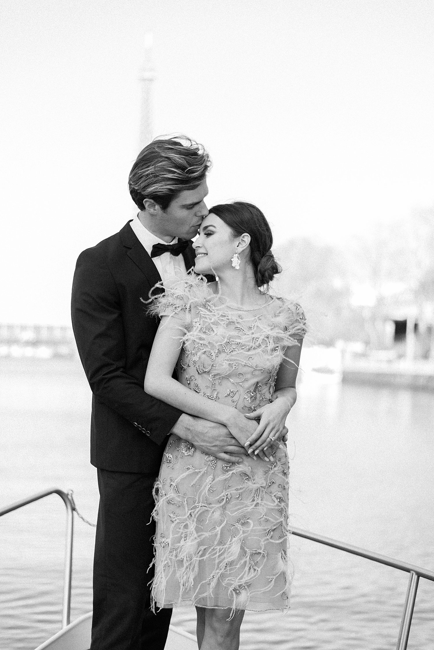 groom kisses bride's forehead on boat floating down River Seine