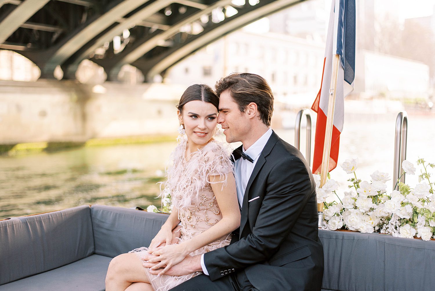 bride nd groom sit on boat on River Seine