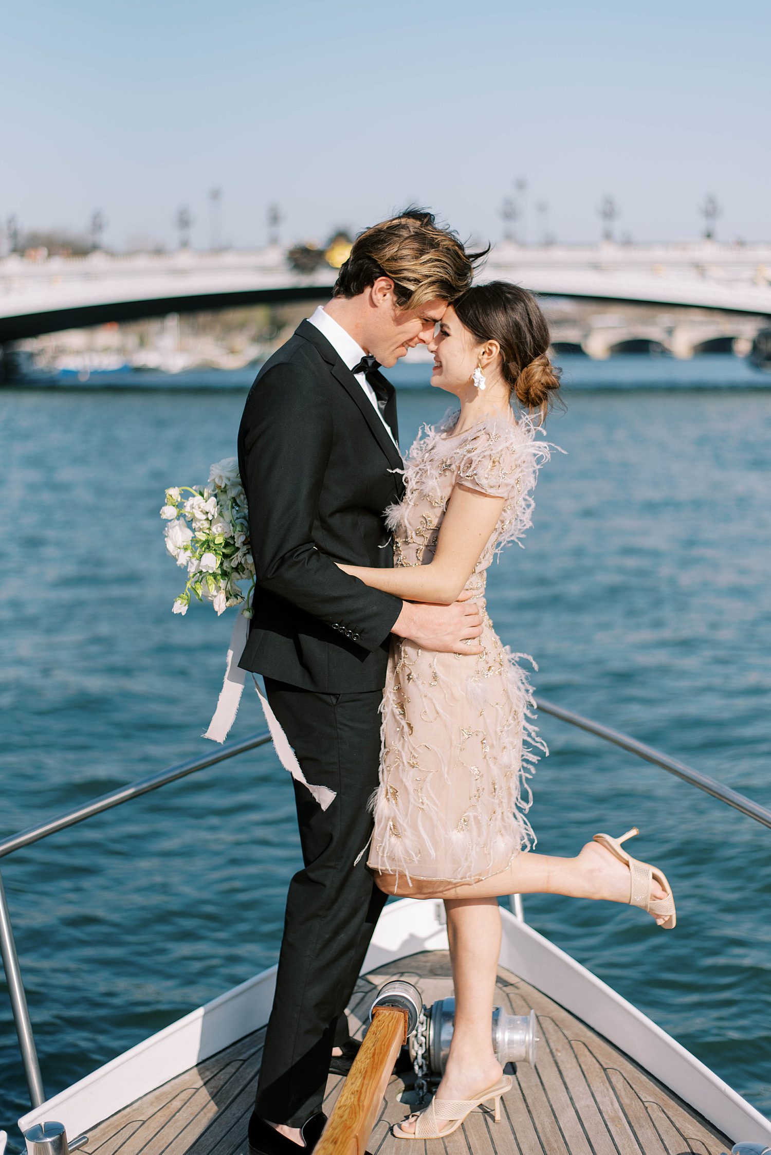 bride and groom hug on front of boat with bride's foot popped