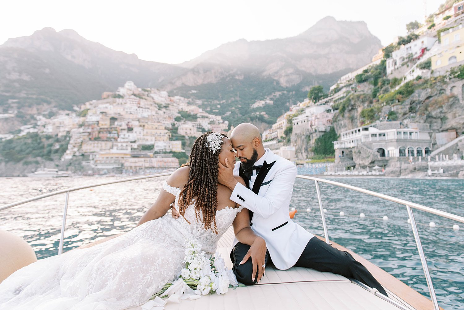 bride and groom sit on the front of boat during Amalfi Coast elopement