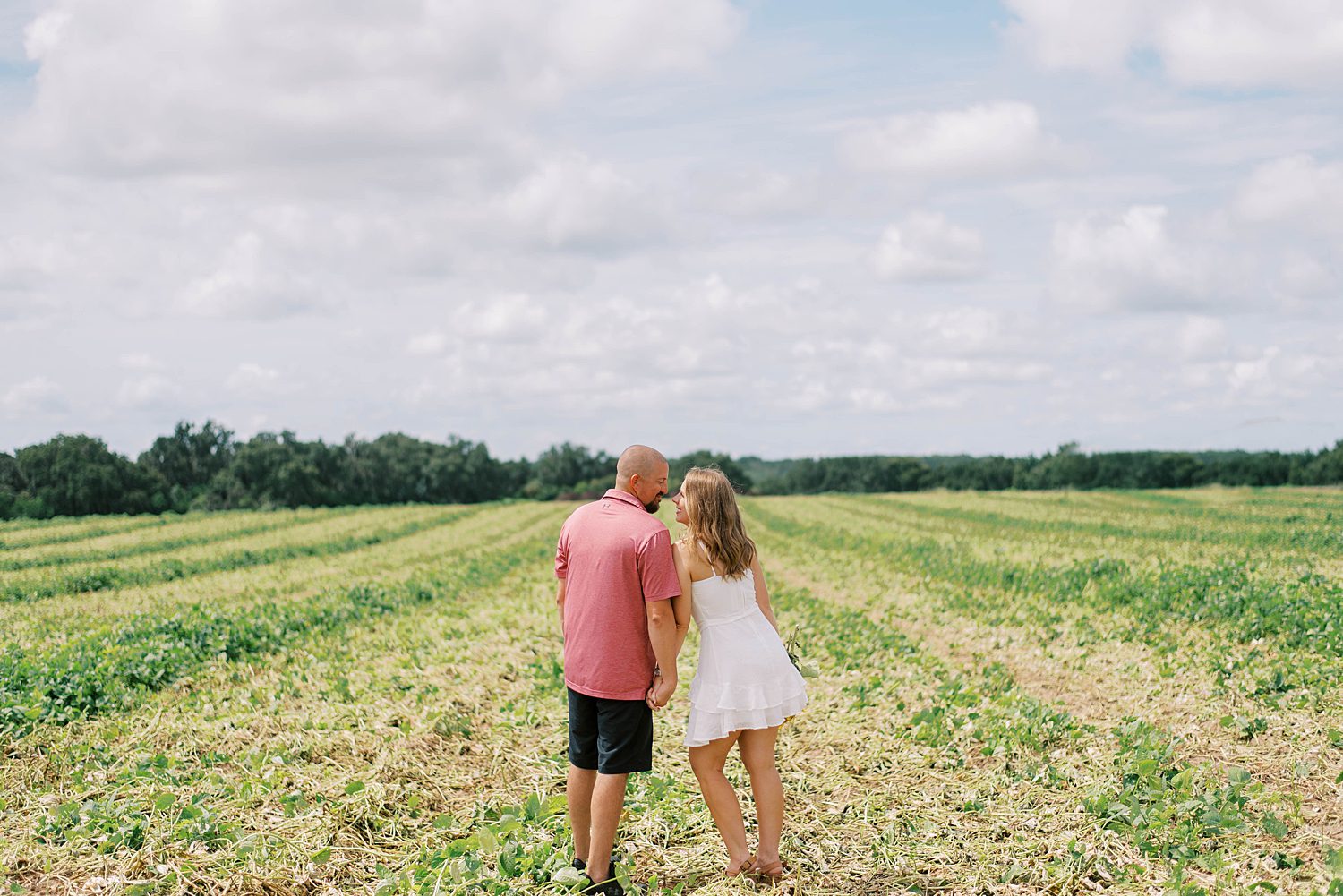 couple leans together during Florida engagement photos in sunflower field 
