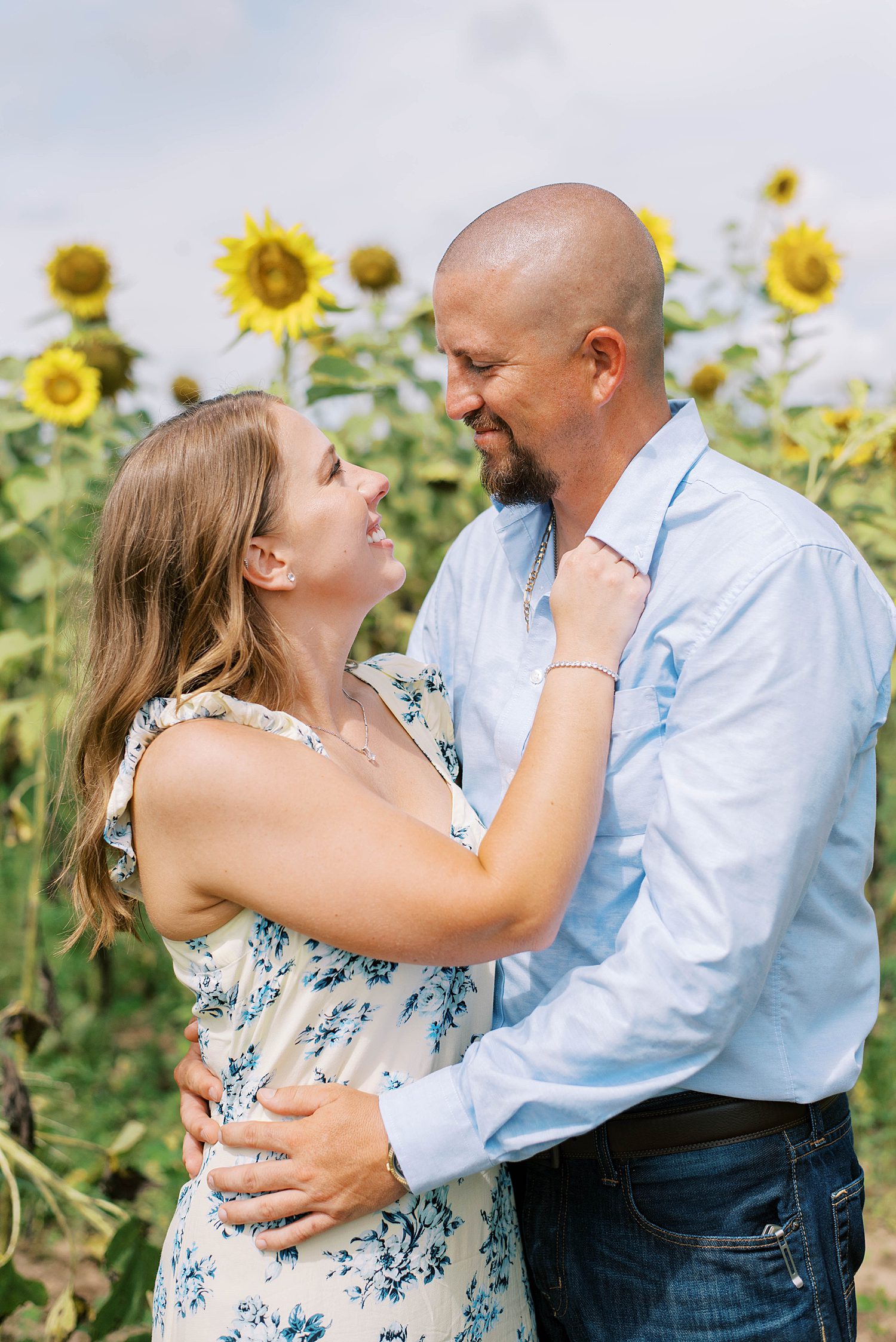 engaged couple smile together next to sunflowers 