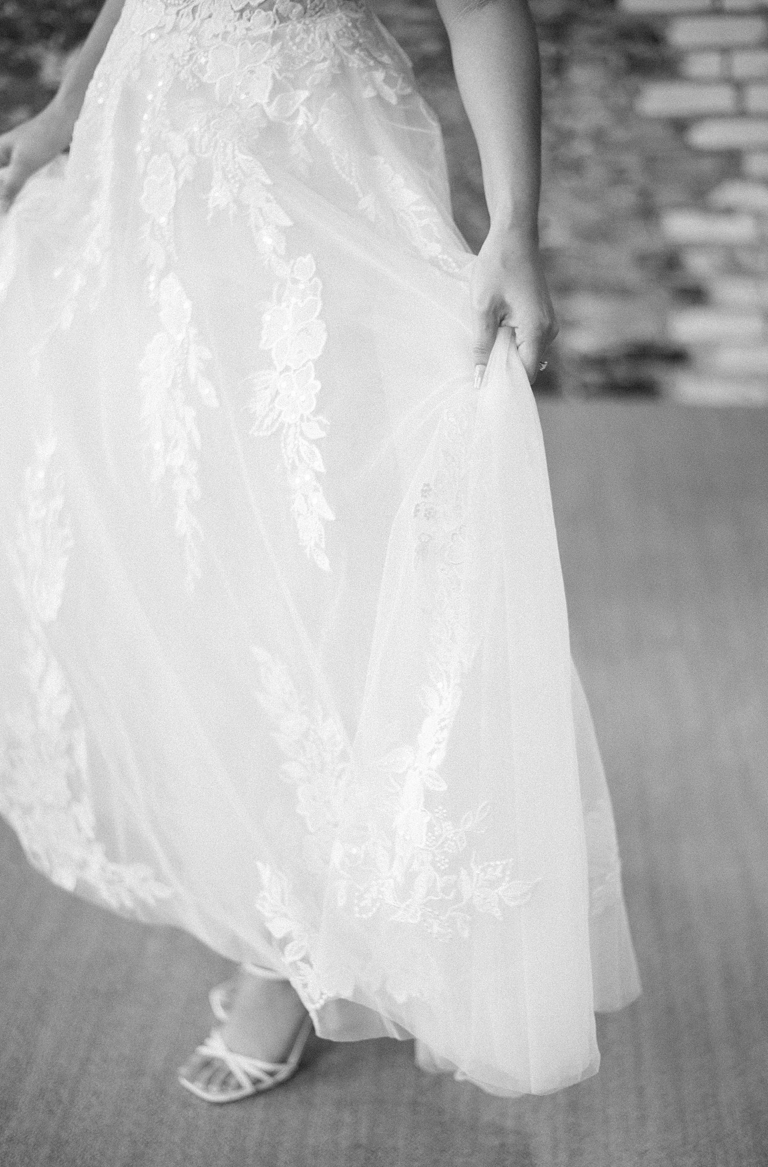 bride shows off lace details on Justin Alexander wedding dress