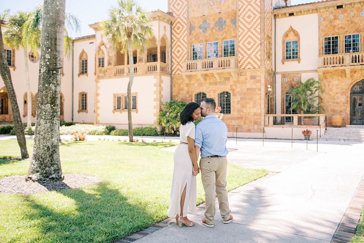 man leans to kiss woman's head during the Ringling Museum engagement session