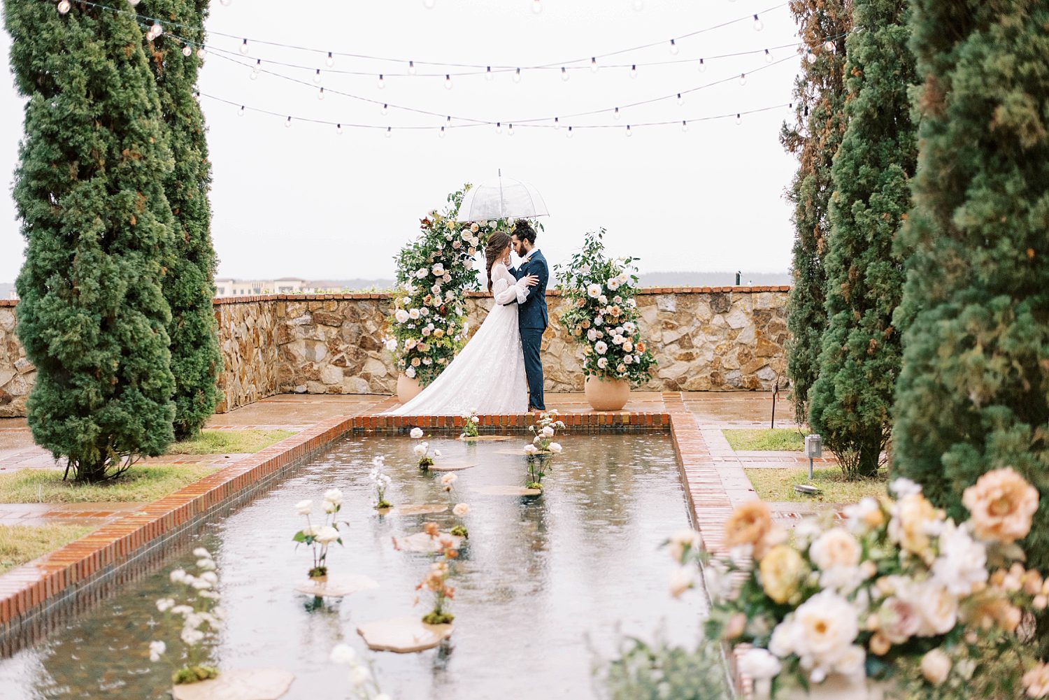couple poses by pond at Bella Collina during rainy Florida wedding day