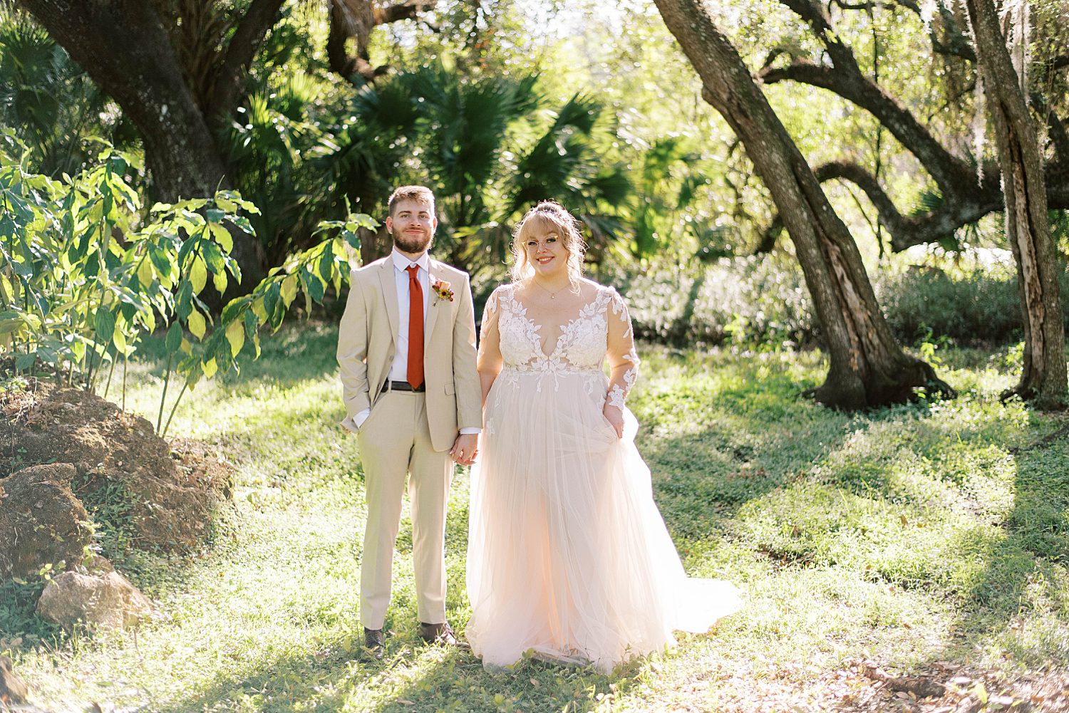 bride and groom hold hands standing between trees in Tampa FL