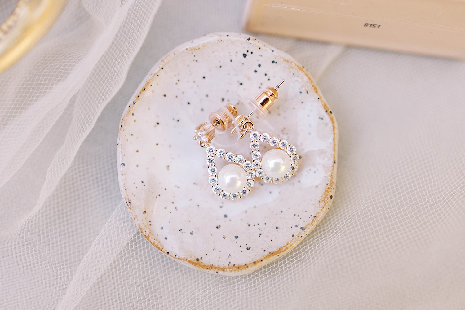 pearl earrings rest on white and gold flecked tray
