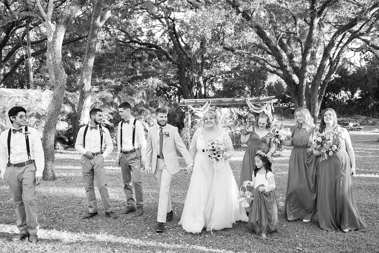 bride and groom walk with wedding party at Events Under the Oaks