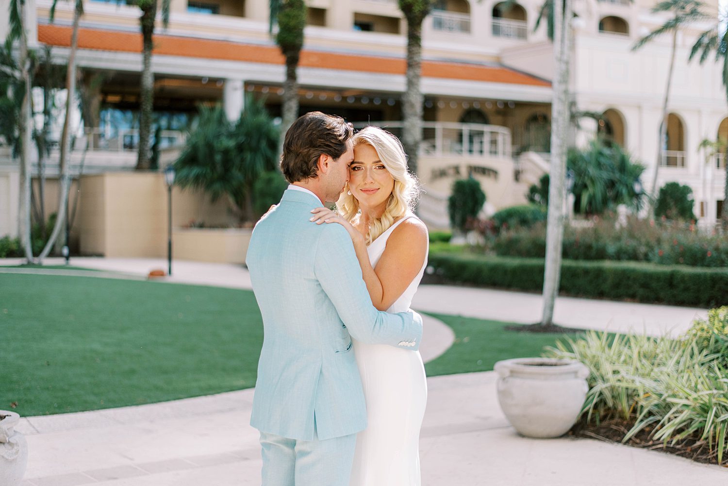 bride and groom hug outside the Ritz Carlton Sarasota between palm trees