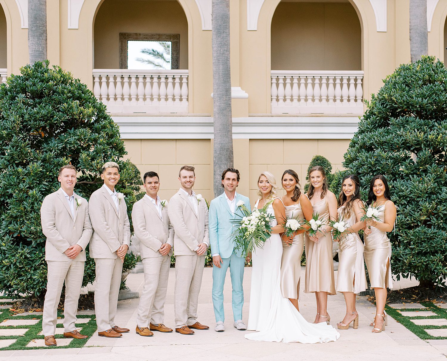 bride and groom pose with wedding party in tan and Champagne gowns
