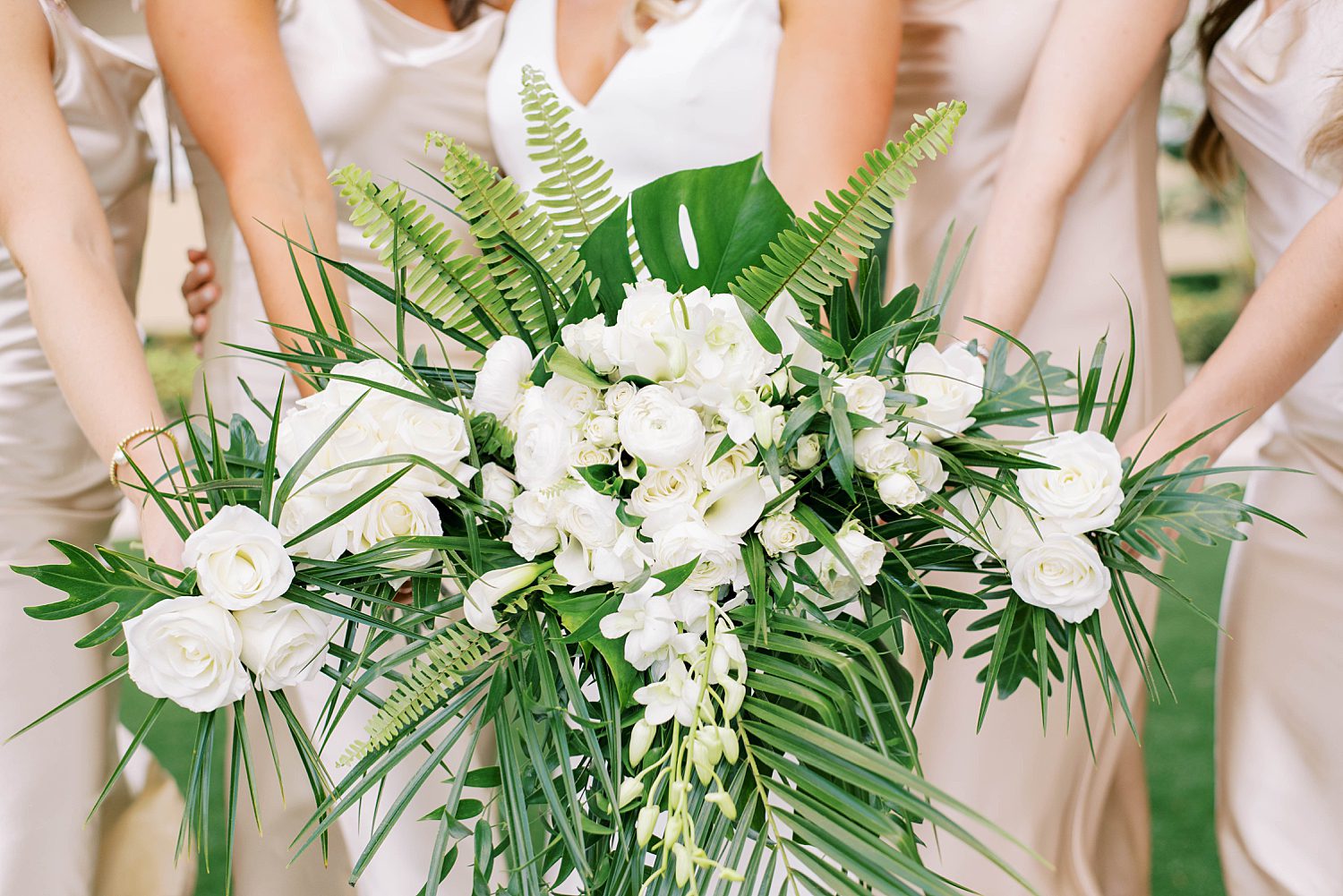 bridesmaids hold tropical bouquets with white flowers and greenery