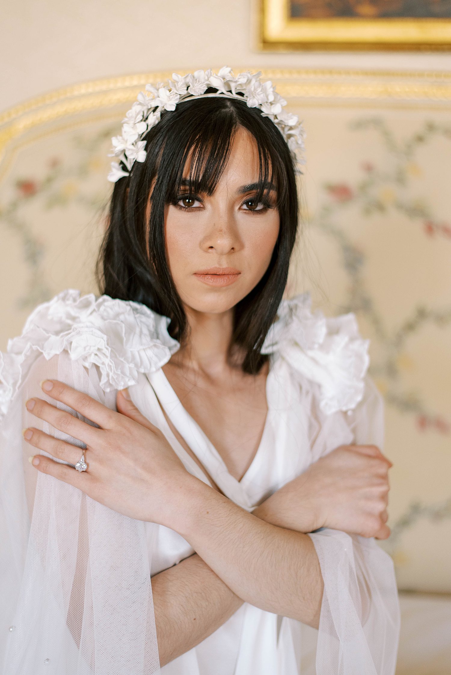 bride looks at camera while holding slip around shoulders during Paris bridal boudoir session at the Ritz