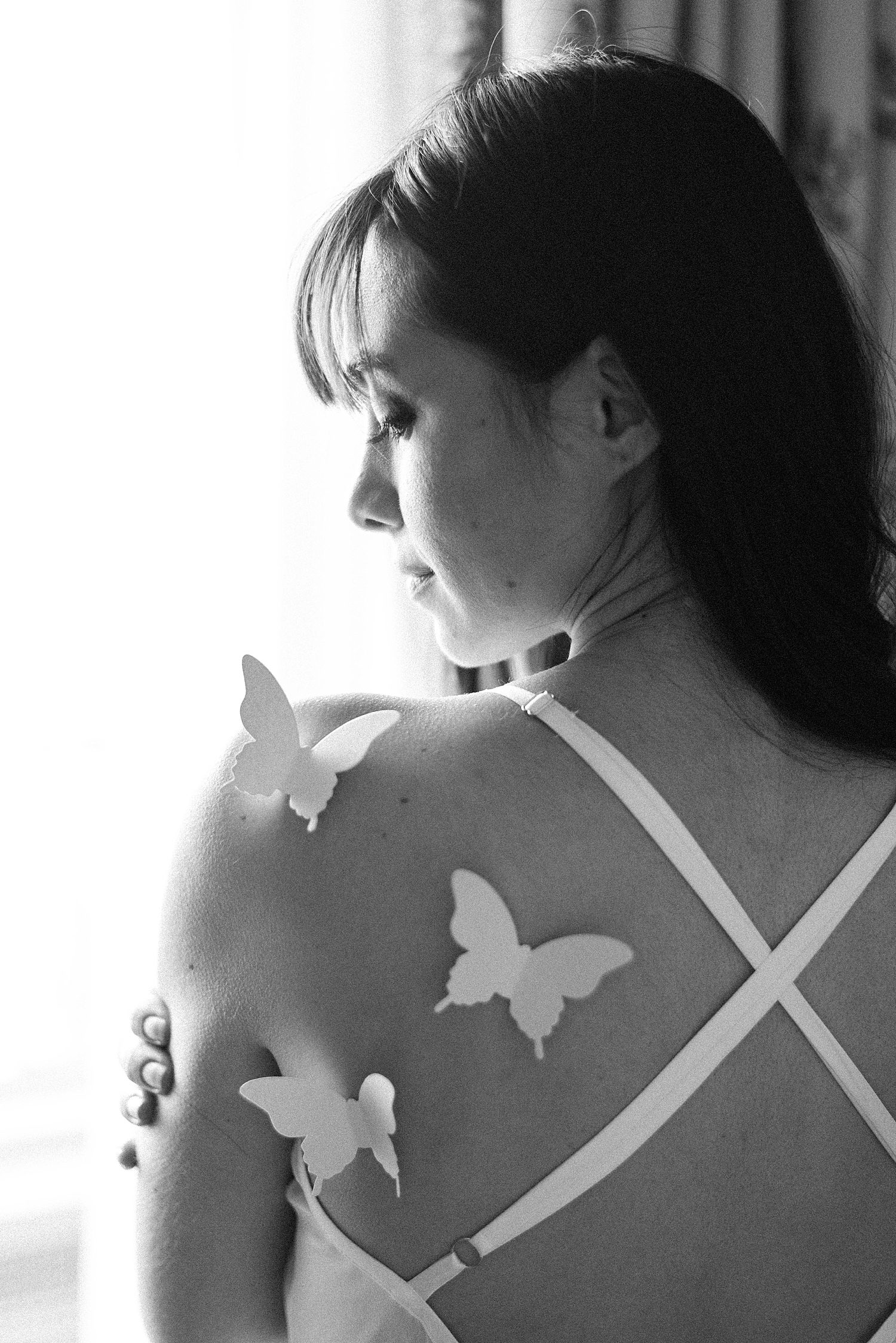 black and white portrait of bride looking over shoulder at butterflies