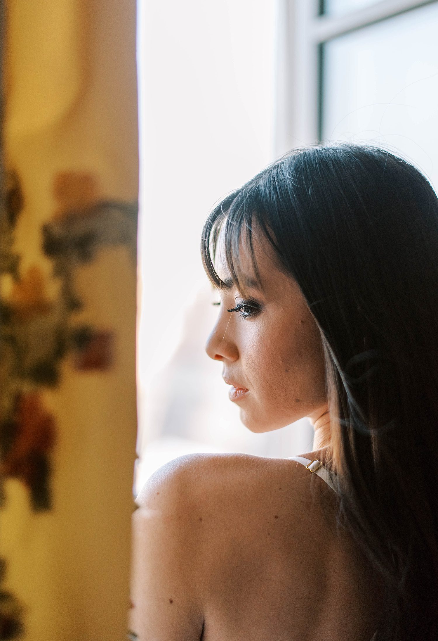 bride looks over bare shoulder during Paris bridal boudoir session at the Ritz