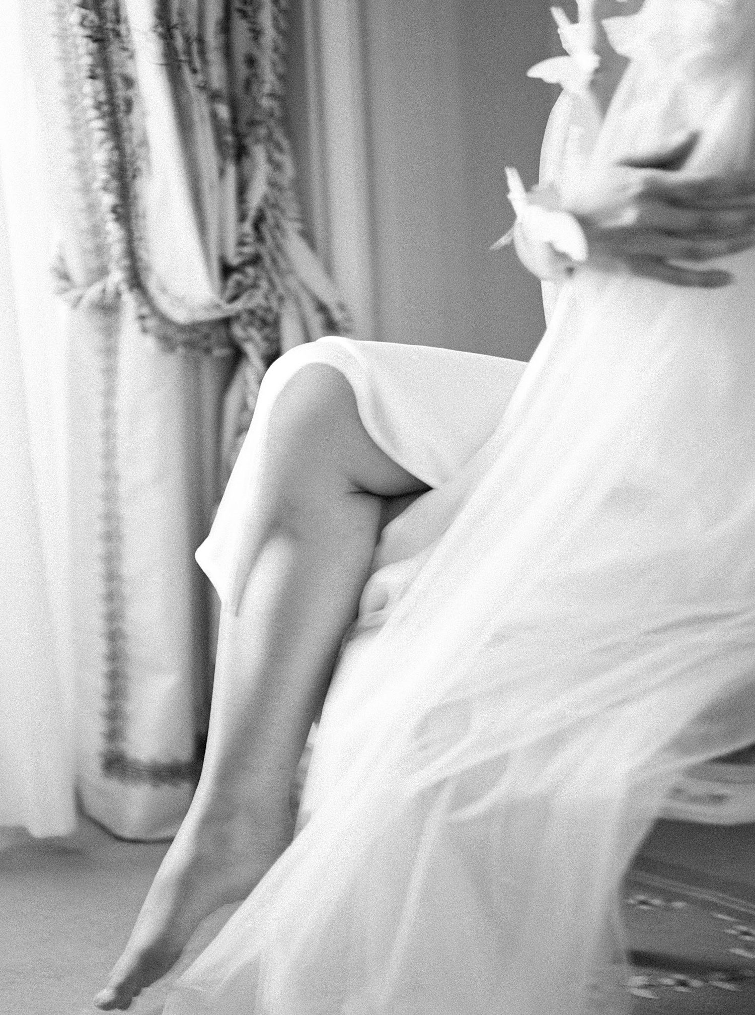 bride shows leg through skirt during Paris bridal boudoir session at the Ritz