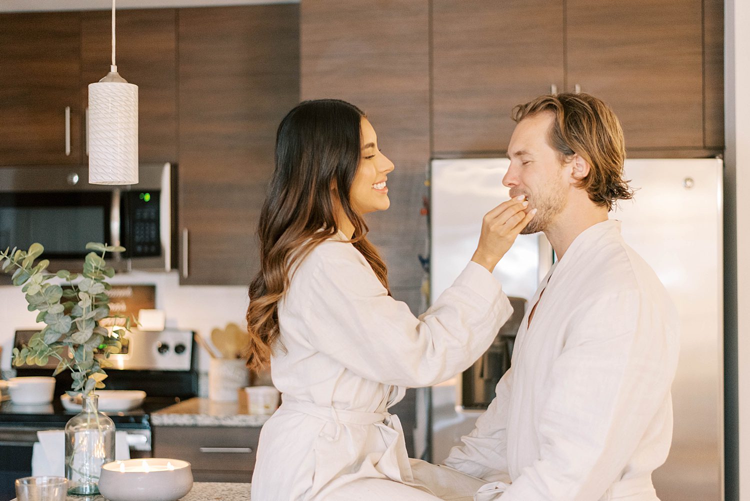 woman feeds husband during lifestyle anniversary portraits in kitchen