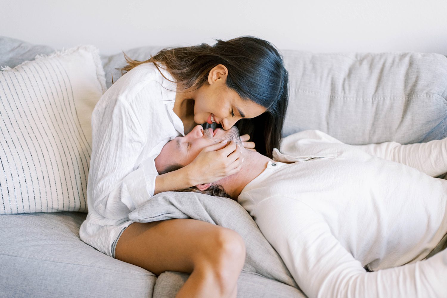 woman leans to kiss husband during portraits at home
