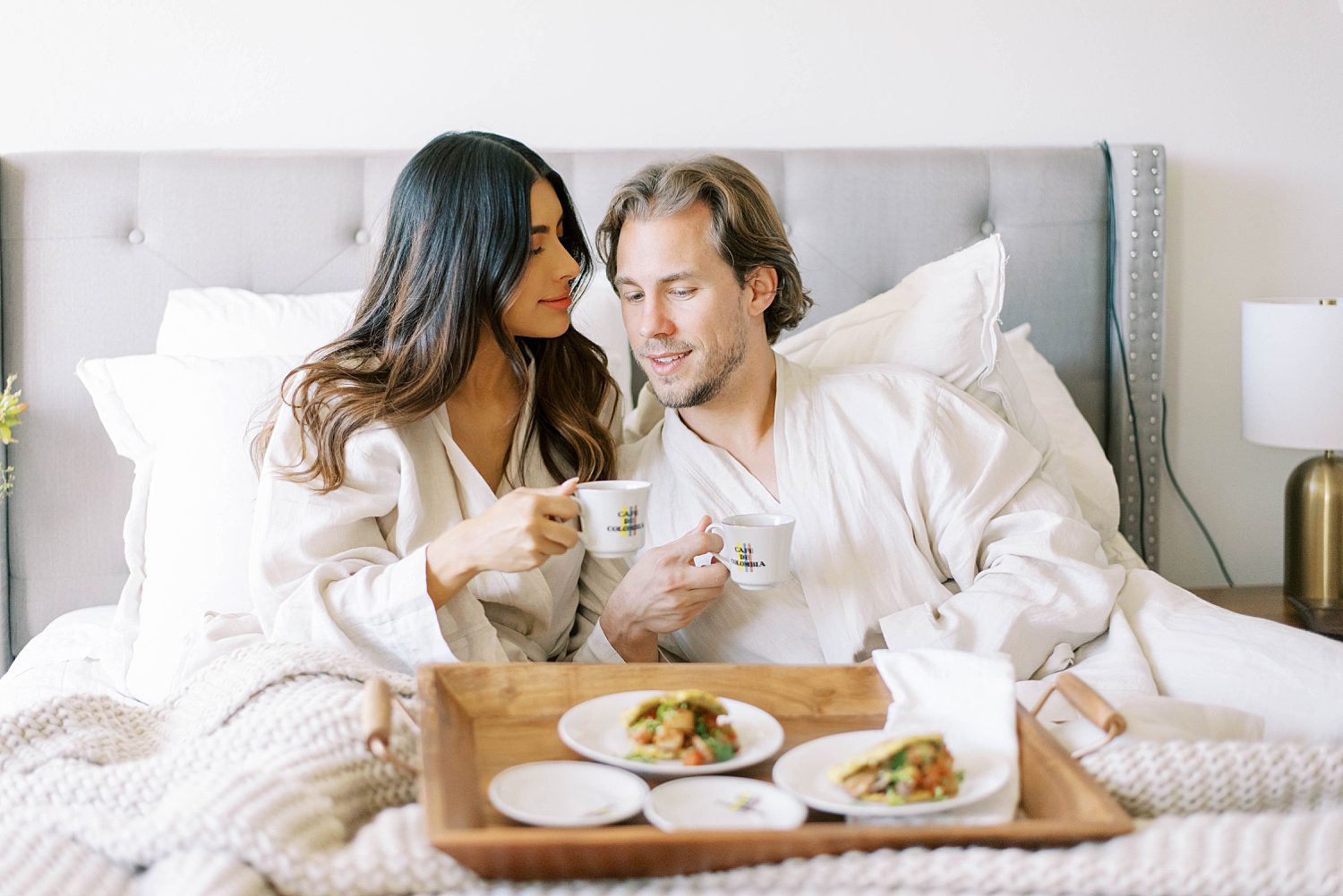 couple sits together in bed eating breakfast
