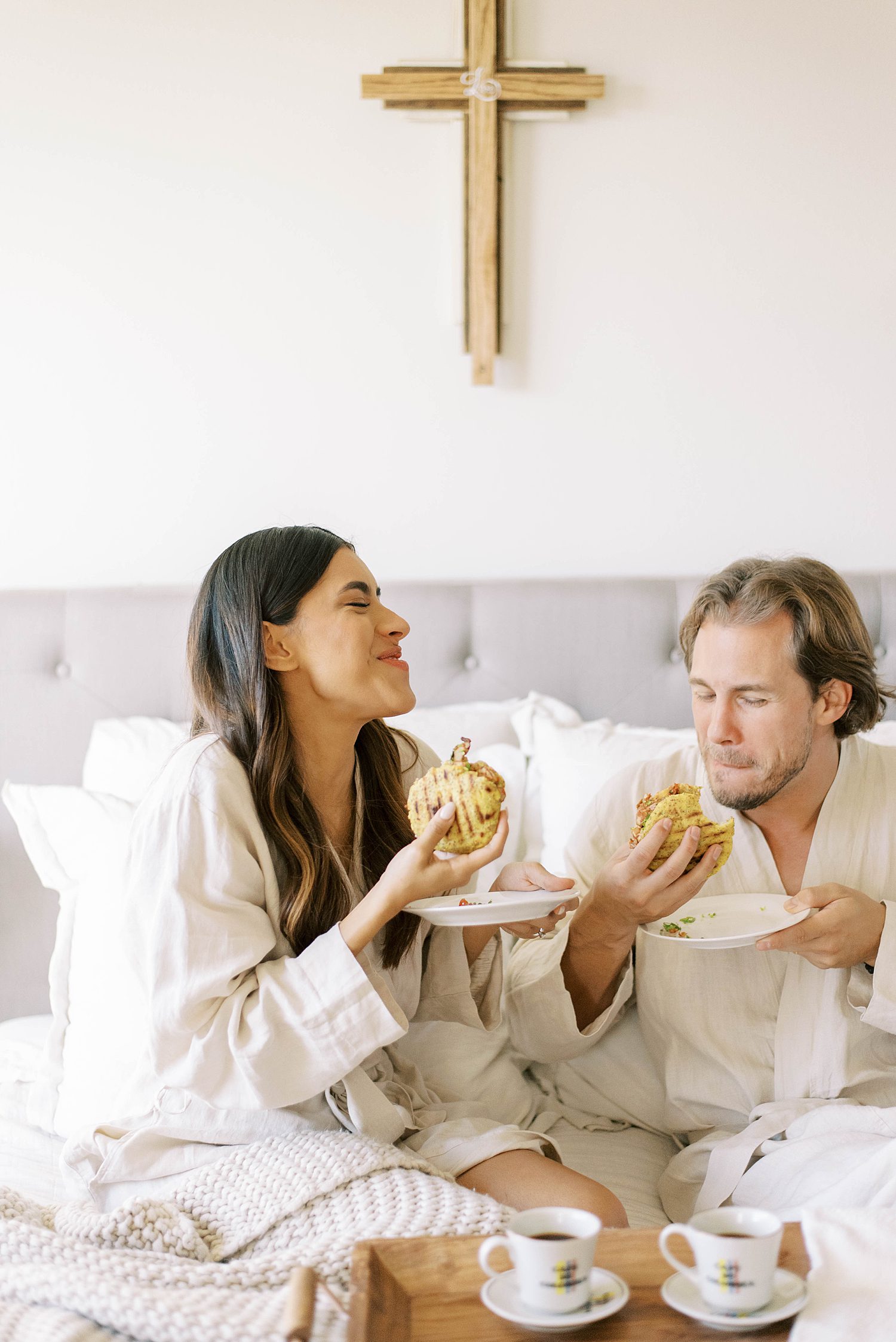married couple laughs during breakfast in bed