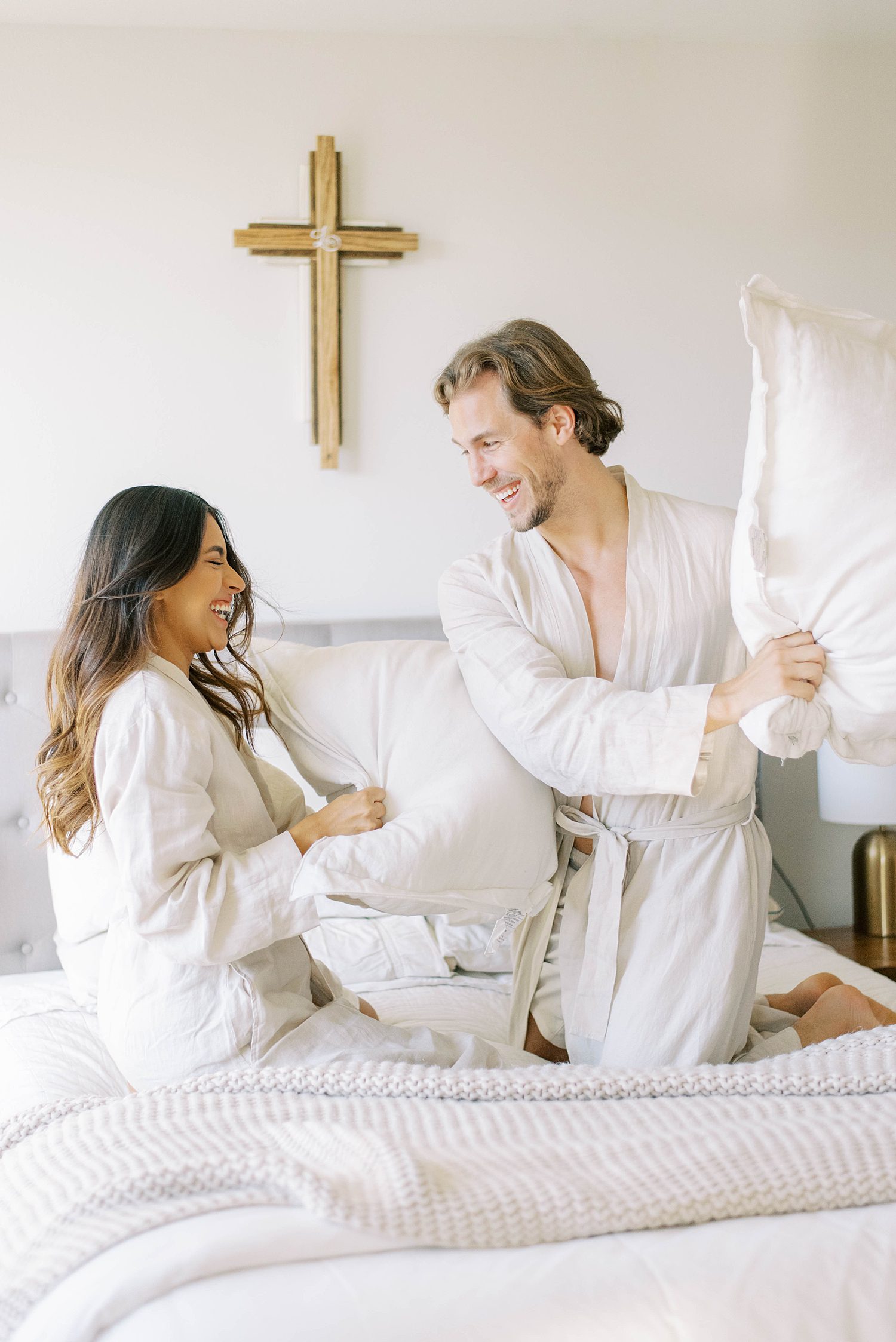 couple has pillow fight during lifestyle anniversary portraits