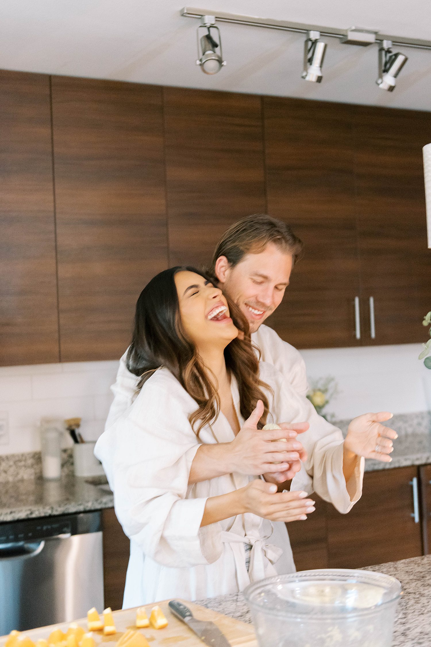 married couple laughs during lifestyle anniversary portraits in kitchen