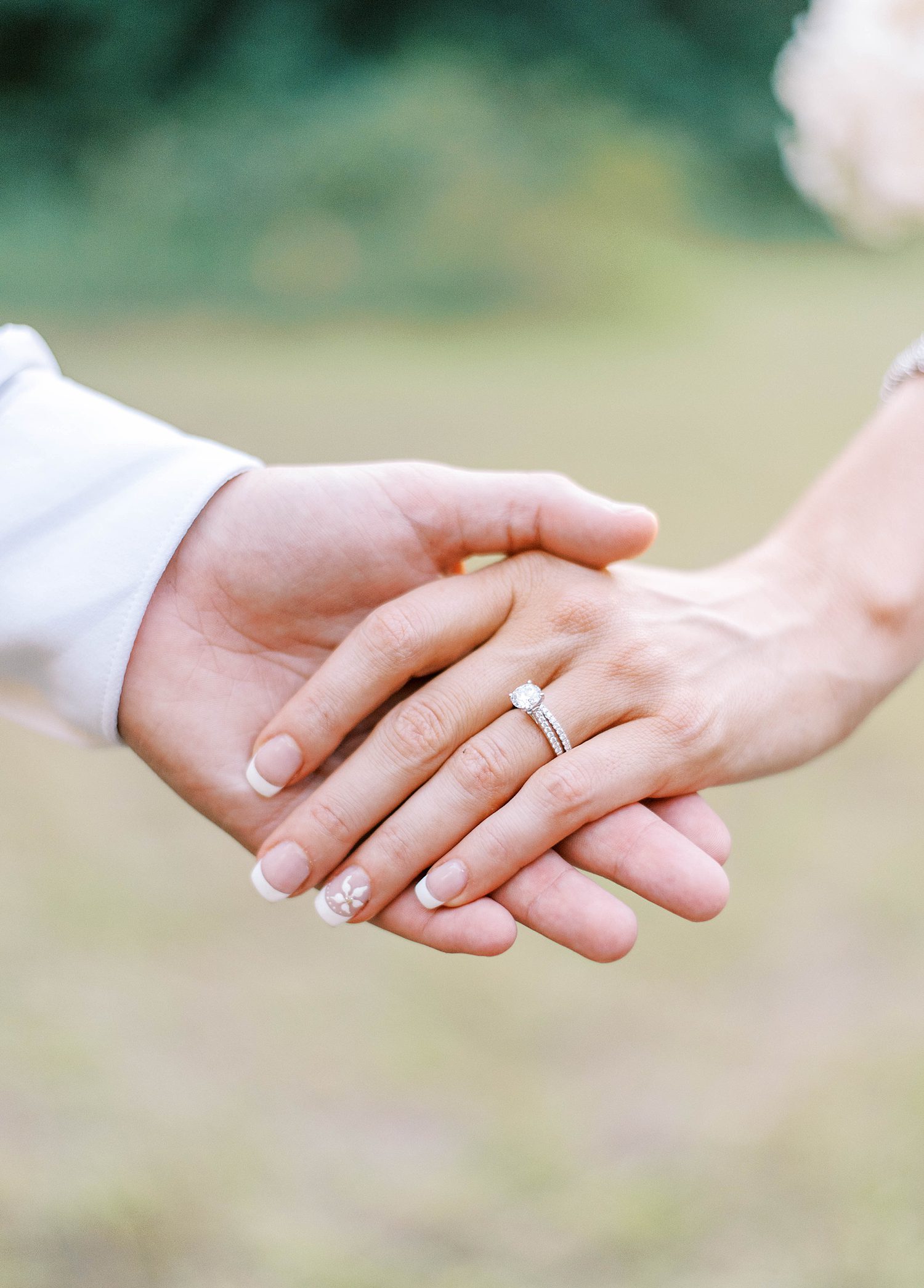 groom holds bride's hand showing off engagement ring