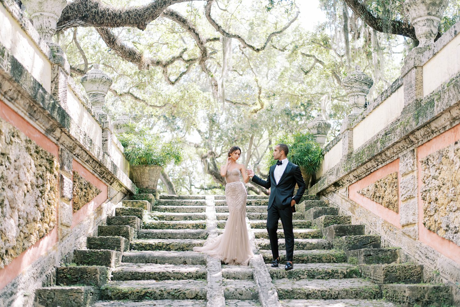groom helps bride down step at Vizcaya Museum in Tampa FL