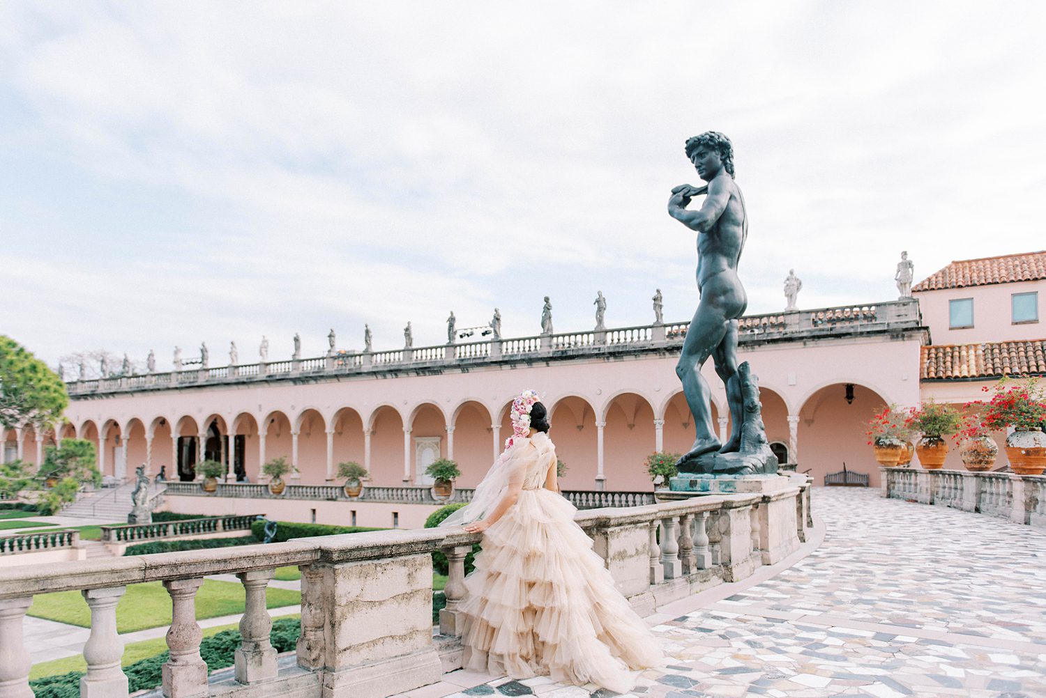 bride in pink textured gown looks over balcony at The Ringling Museum
