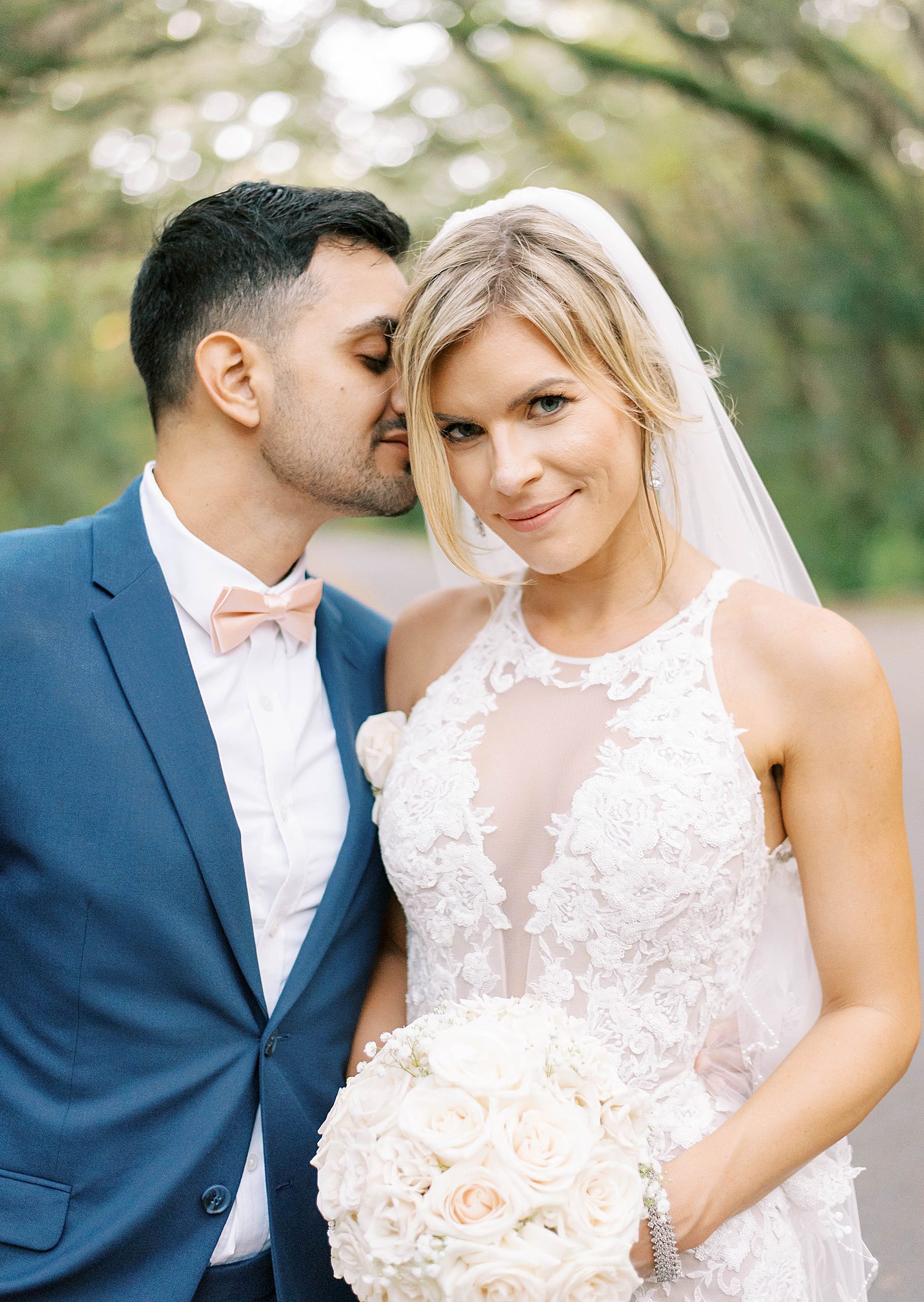 groom in navy suit leans to kiss bride's forehead at Philippe Park