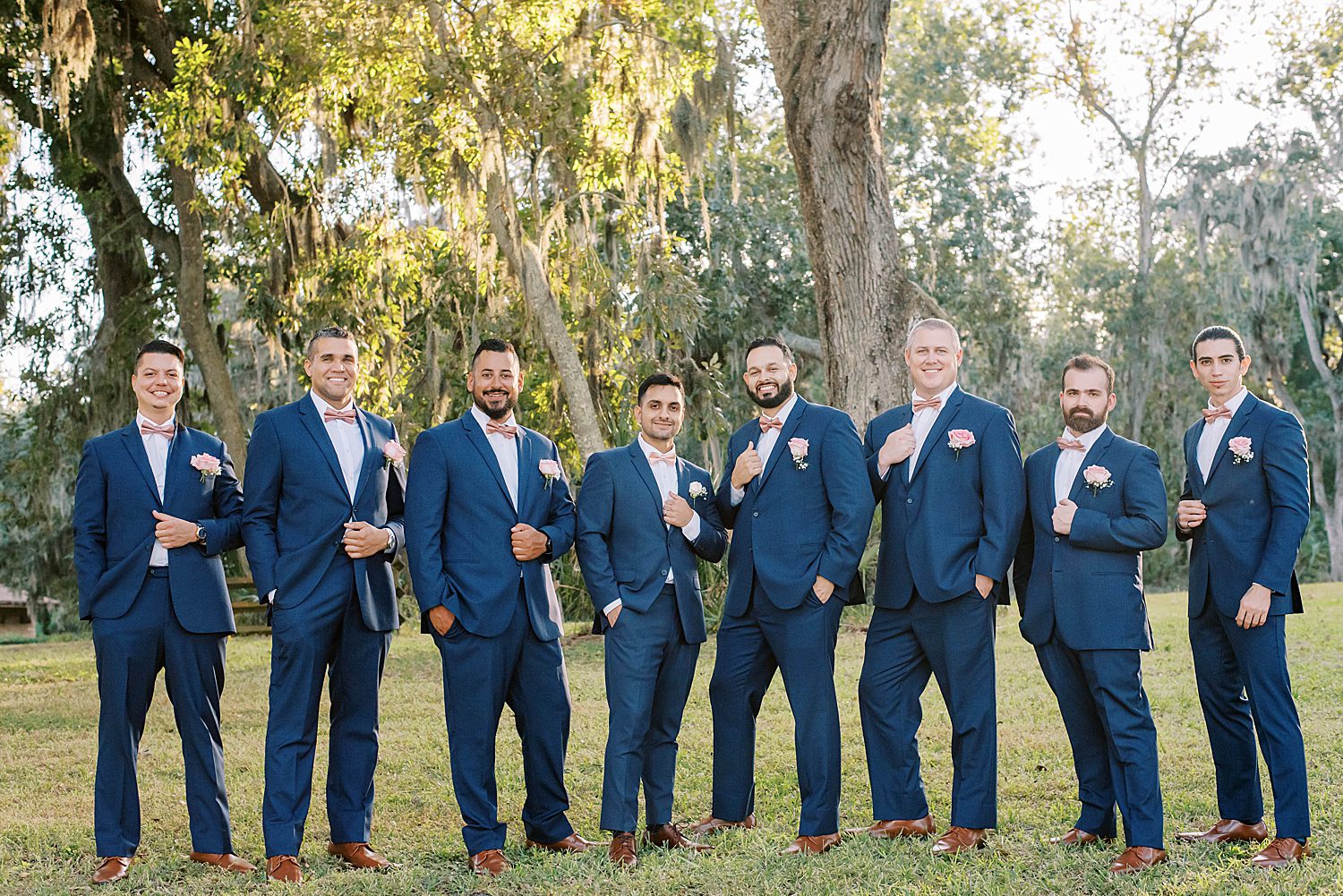 groom stands with groomsmen in navy suits at Philippe Park