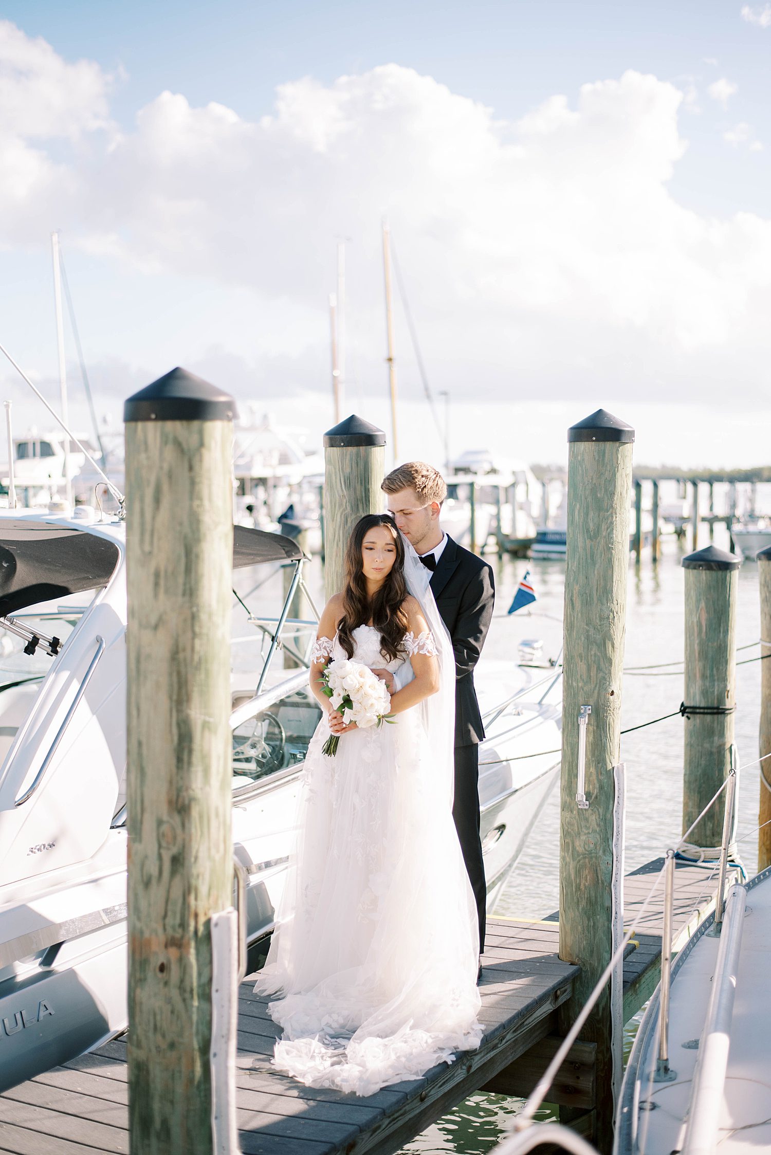 groom hugs bride from behind on dock at Sarasota Yacht Club